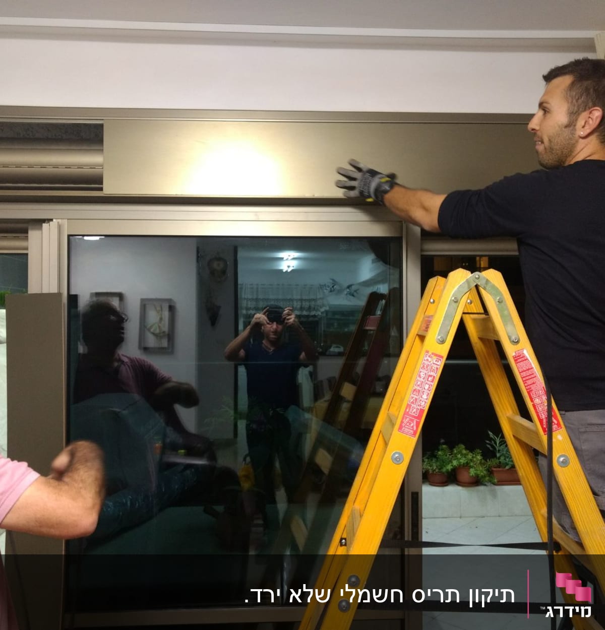 שני אנשים מתקינים תריסים על חלון גדול